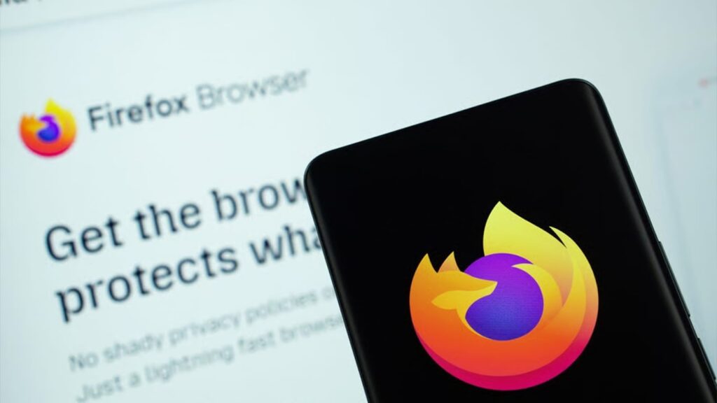 Close-up of a smartphone screen displaying the Mozilla Firefox browser logo against a black background, with the Firefox website visible in the blurred background.
