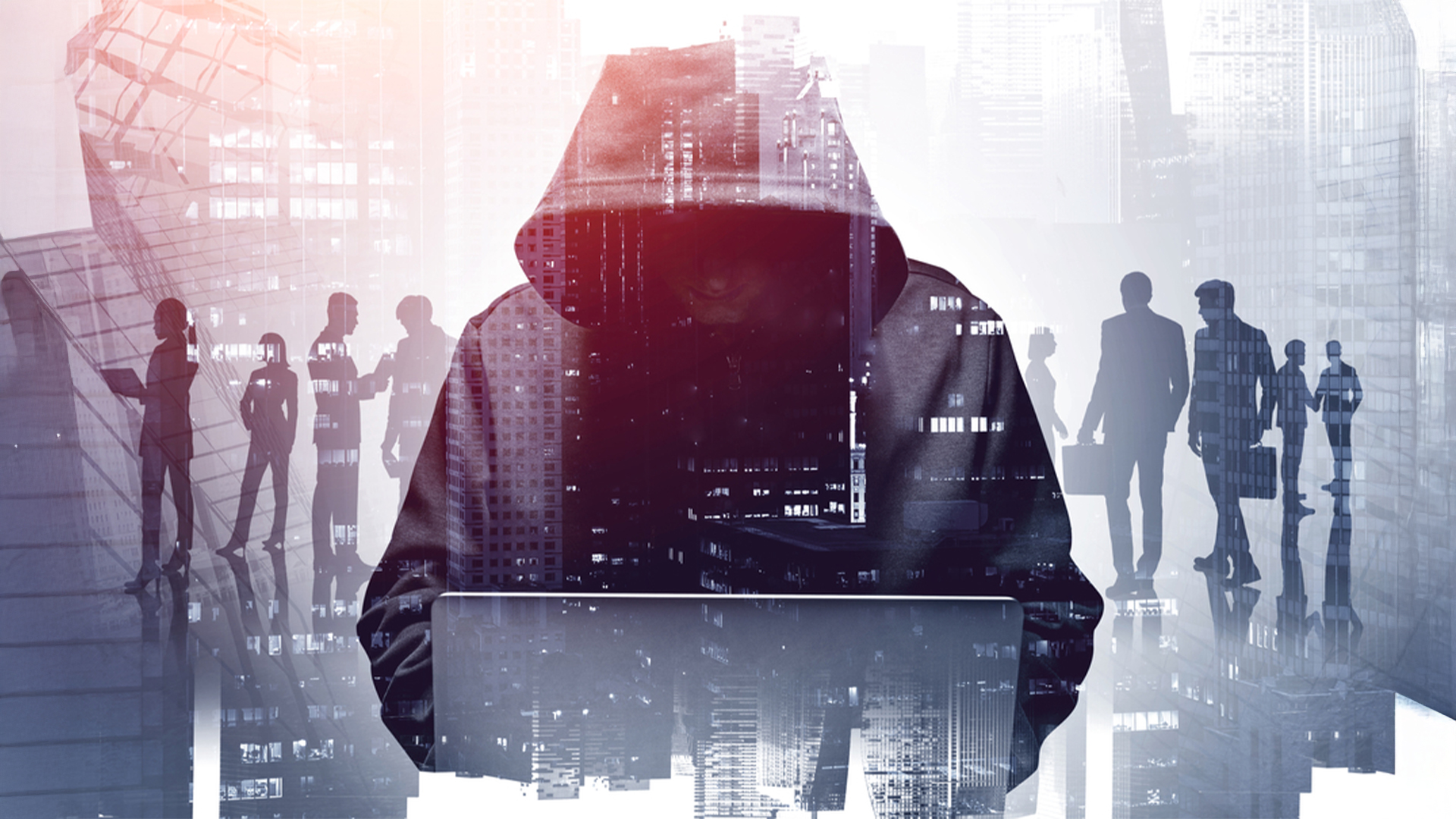 Hacker in a hoodie using a laptop which symbolises hacking with city & silhouettes of business professionals in the background
